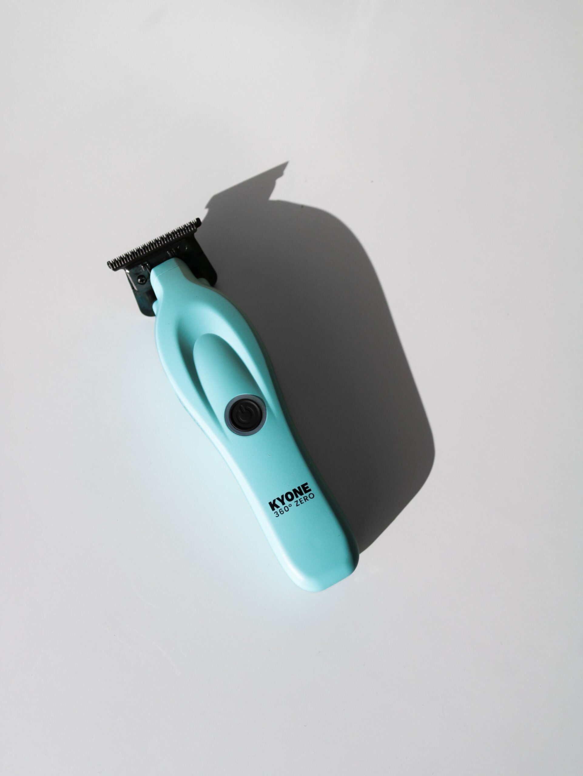Kyone 360 Zero-trimmer i blått mot ljus bakgrund med skarp skugga