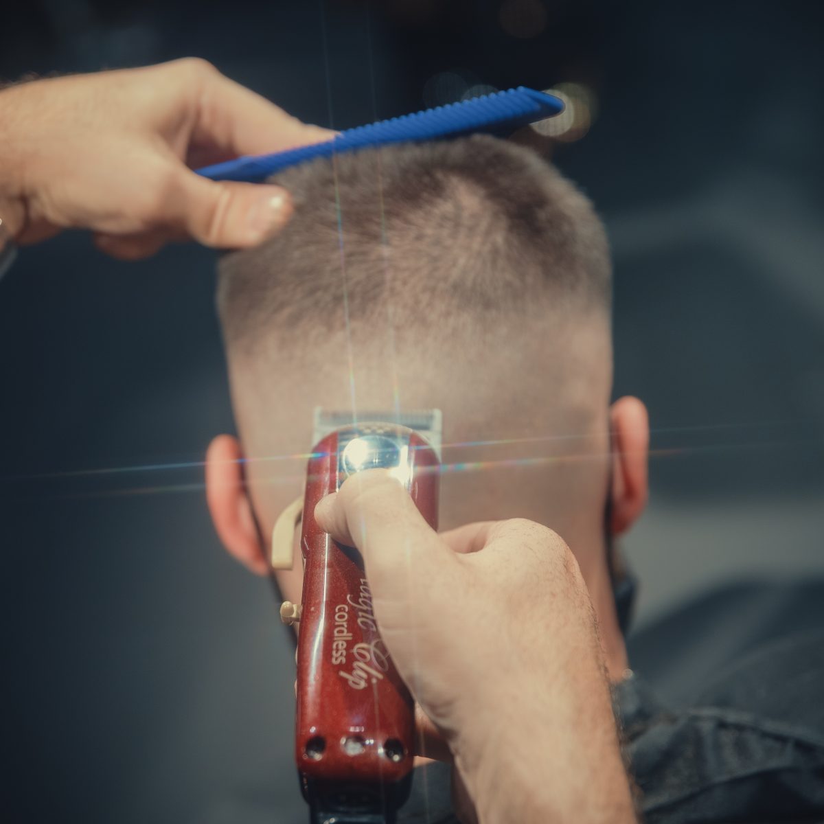 Barberare klipper en fade i nacken med Wahl Cordless Magic Clip och blå kam